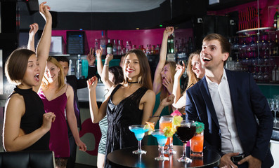 Wall Mural - Colleagues dancing on corporate party with cocktails in hands