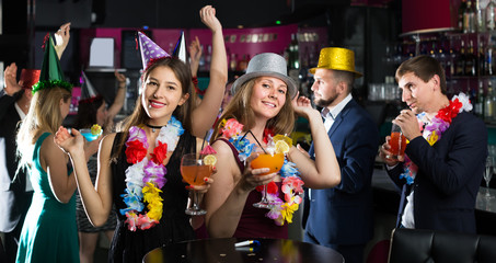 Wall Mural - Portrait of young smiling women and men in caps with cocktails