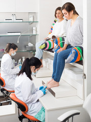 Pair of women clients getting pedicure in modern nail salon