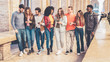 group of interracial friends meeting in the city center. they are having fun with smart phones and social media, walking together and chatting together.