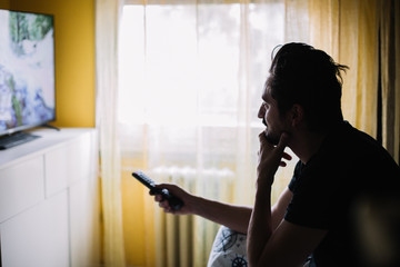 Man holding TV remote and watching