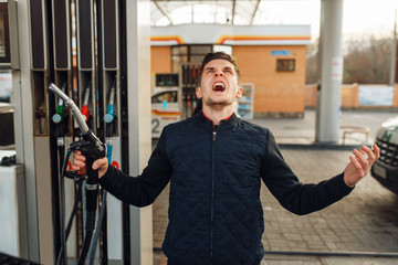 Depressed man cries on gas station, fuel filling