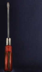 Red flathead screwdriver on a blue background, tool