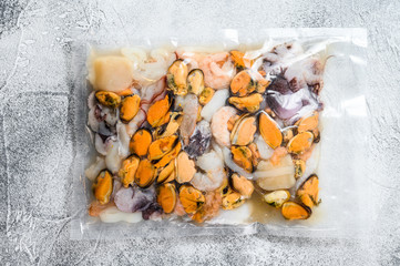 Raw seafood mix in vacuum packaging. Gray background. Top view