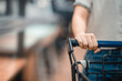 © oatawa - Close up hand of female shopper with trolley, shopping cart at supermarket.