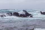 Fototapeta Morze - Beautiful Nature scene of sea wave hitting on the black stone shoreline at Jeju Island, South Korea.