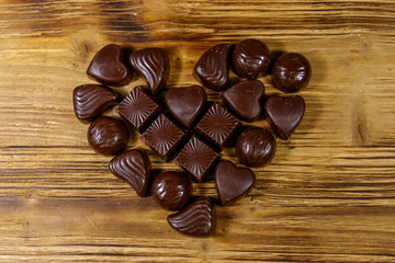 Wall Mural - Heart shape made of different chocolate candies on wooden table. Top view. Valentine Day concept