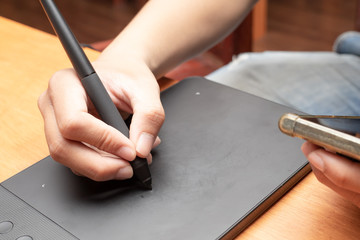 Close up of man's hand using a digital tablet and stylus pen. drawing practice, professional designer, graphic designer.