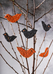 Beautiful birds created from red and black lentils hanging on branches. Handmade easter decoration concept. Selective focus.