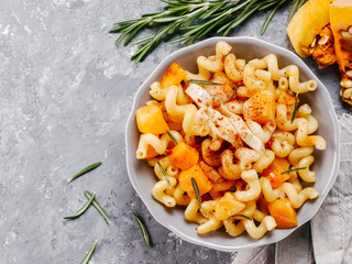 Wall Mural - Fusilli pasta with pumpkin, rosemary and brie cheese. Idea recipe pasta. Vegetarian food. Homemade pasta dish in gray bowl over gray concrete background. Copy space. Top view or flat lay.