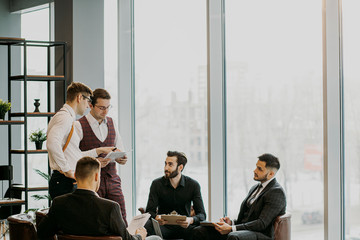 coworking of handsome guys in tuxedo, isolated in modern office. teamwork of successful people gathered to develop business project and have conversation, discussion