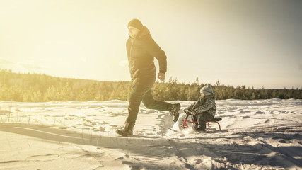 Wall Mural - Father rides his son on a sled in winter	