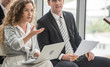 © supAVADEE BUTRADEE - Businesswoman holding laptop and sitting in a seminar with a marketing male friend and an employee had questions about the coaching job in the company's meeting room.