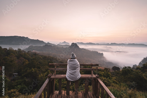 Fotomural Young woman traveler looking at sea of mist and sunset over the mountain