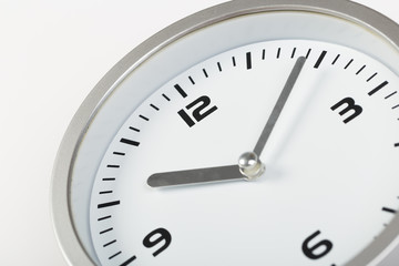 10 minutes after ten white with light metal minimalistic clock close-up on a light background