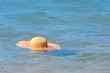 Yellow wicker straw hat floating in blue sea water