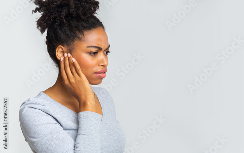 Fotografía Afro girl suffering from otitis, rubbing her inflamated ear