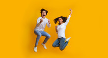 Overjoyed Multiracial Couple Jumping In The Air And Celebrating Success