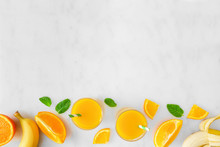 Healthy Orange Banana Smoothie Bottom Border. Top View In Glasses Over A White Marble Background. Copy Space.