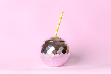 Creative disco cocktail shaped ball cup and paper straw with flash effect sparkle and shine on pink background. Concept for holidays and parties.