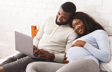 Lovely Pregnant Couple Using Laptop While Resting