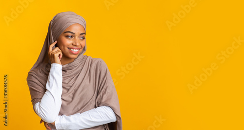 Fotografía Interested black muslim girl looking away at copy space on yellow background