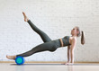 © junky_jess - Reverse plank exercise with foam roller. Young fit woman does pilates in loft fitness studio, indoor.