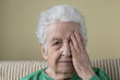 © berna_namoglu - a senior woman her one eye with her wrinkled hand