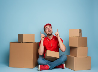 Wall Mural - Courier is happy and indicates something above. Studio on cyan background