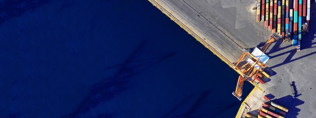 Aerial drone ultra wide top down photo of commercial container terminal with cranes loading shipment to tanker ships in Mediterranean port