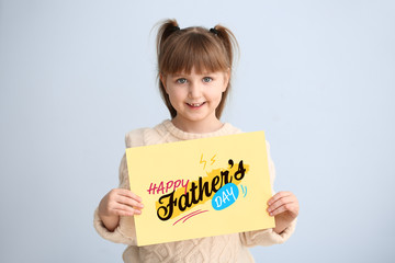 Wall Mural - Cute little girl with greeting card for Father's Day on light background