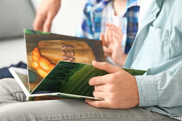 Wall Mural - Father and his little son reading book at home, closeup