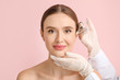 © Pixel-Shot - Young woman receiving filler injection against color background