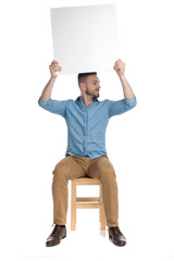 Wall Mural - young casual man holding empty board above head