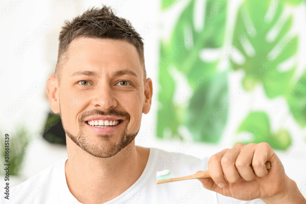 Handsome man brushing teeth at home