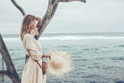 Fotografía Boho model wearing dress and straw hat on the beach