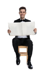 Wall Mural - young elegant man holding newspaper and smiling