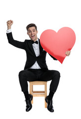 Wall Mural - young elegant man celebrating victory and holding big heart