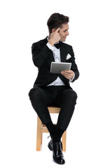 Wall Mural - young elegant man in tuxedo holding tab