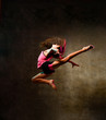 Street dance girl dancer jumping up dancing in neon light doing gymnastic exercises jump in studio on dark wall