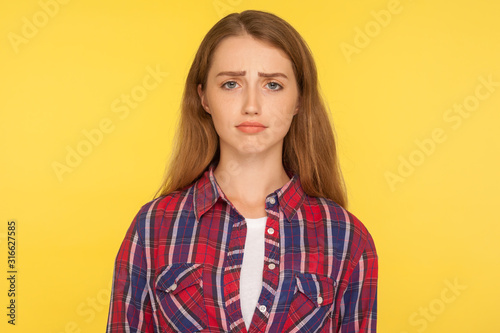 Fotografía Portrait of unhappy ginger girl in checkered shirt frowning and looking at camera with upset dismal expression, feeling insulted, resentful facial emotion