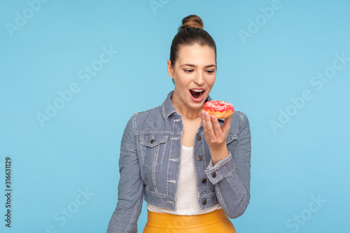 Cuadros en Lienzo Delighted beautiful woman with hair bun looking at delicious doughnut with desire, keeping her mouth opened and dreaming to bite eat sweet donut, temptation of sugary confectionery