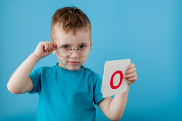 Cute little boy with letter on blue background. Child learning a letters. Alphabet