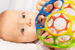 © Sergey Novikov - Beautiful little baby boy play with colorful vivid ball toy and look to camera close-up shoot