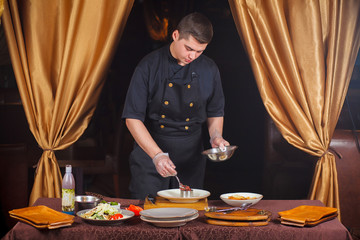 Chef pours the ingredients into the form. Portrait of a cook at work.