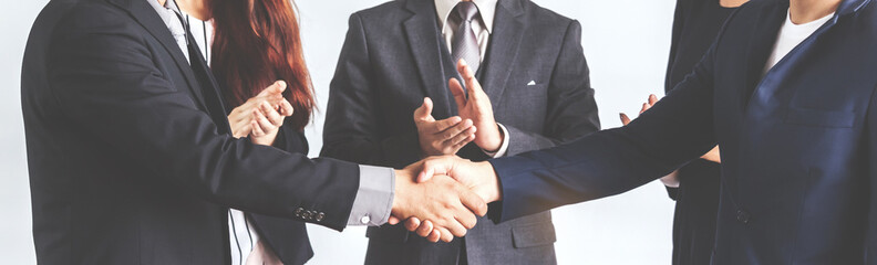 Image two business partners in elegant suit successful handshake together standing in front of group of casual business clapping hands in modern office.Partnership approval and thanks gesture concept