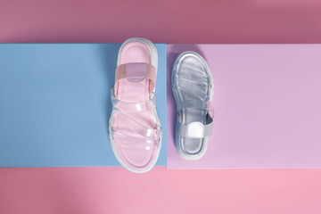 Wall Mural - Fashionable gray and pink open slippers with a white sole and transparent straps stand on a pink, blue stand from the studio. Promotional photo