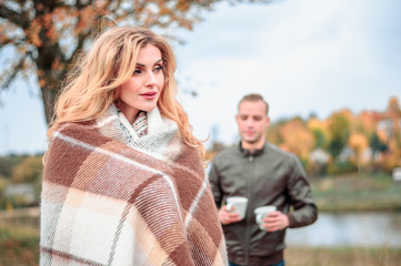 Wall Mural - a guy treats a cup of hot tea to his girlfriend who froze in cold autumn weather and wrapped herself in a plaid, a love story and the concept of caring for a loved one