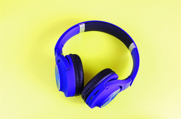 Blue headphones lie on a colorful yellow background. Isolated