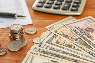 Coin stack with a calculator and dollar bills